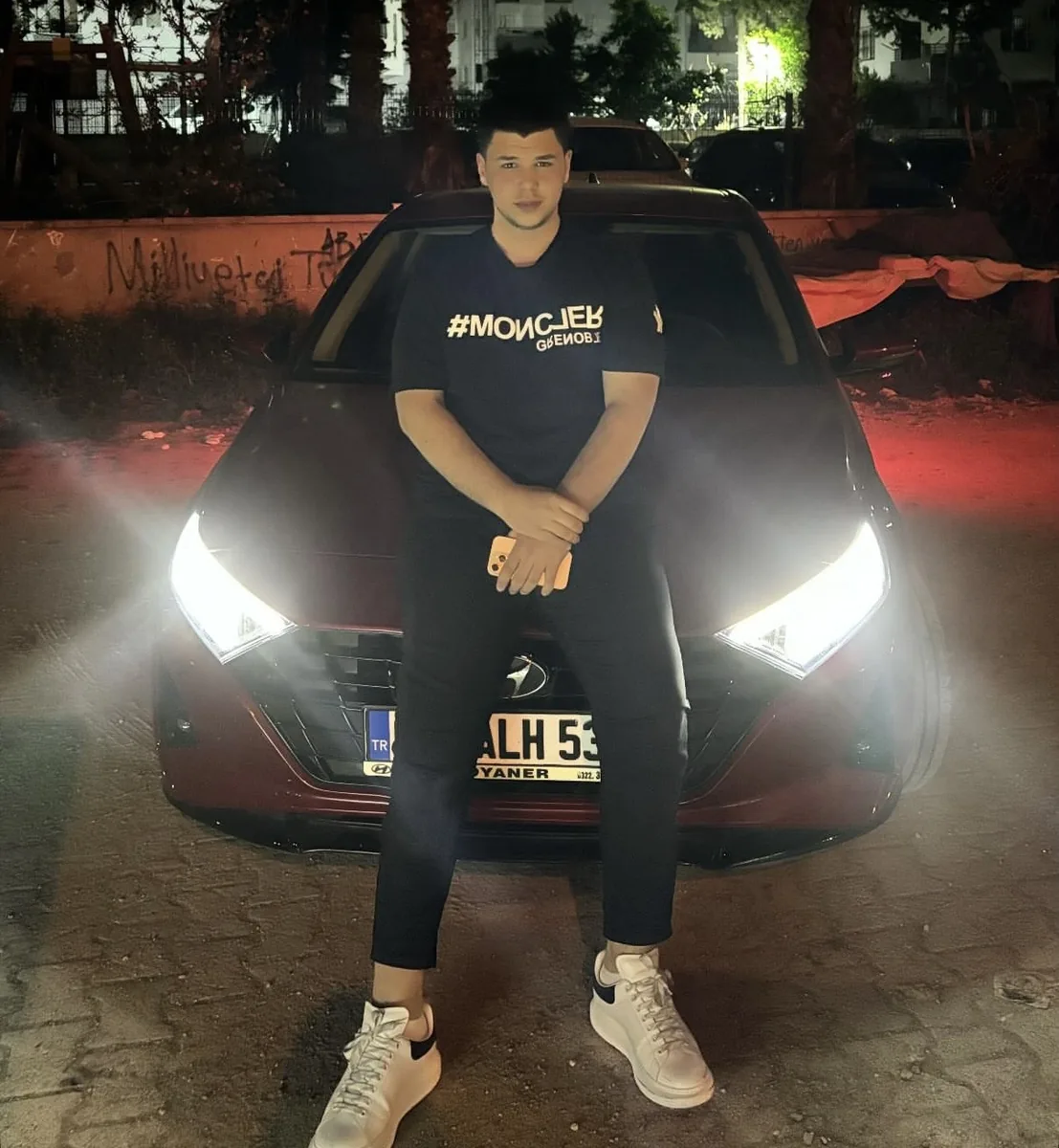 İrfan gece, farları yanan kırmızı arabasının kaputuna yaslanmış